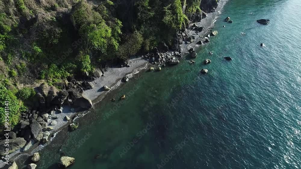 Drone shot of a rugged coastline with emerald waters Drone shot of a rugged coastline with emerald waters