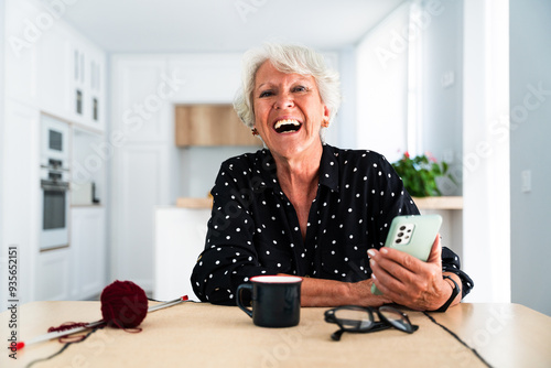 Beautiful senior old woman with gray hair portrait at home using smartphone - Youthful elderly granmother spending quality time at home photo