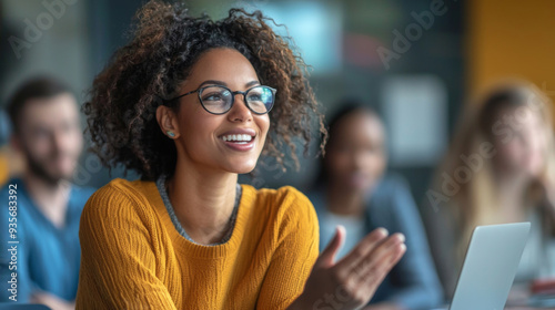 A woman with curly hair and glasses is smiling at the camera