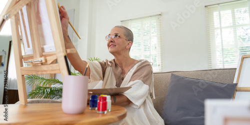 Senior woman painting on easel in cozy home studio