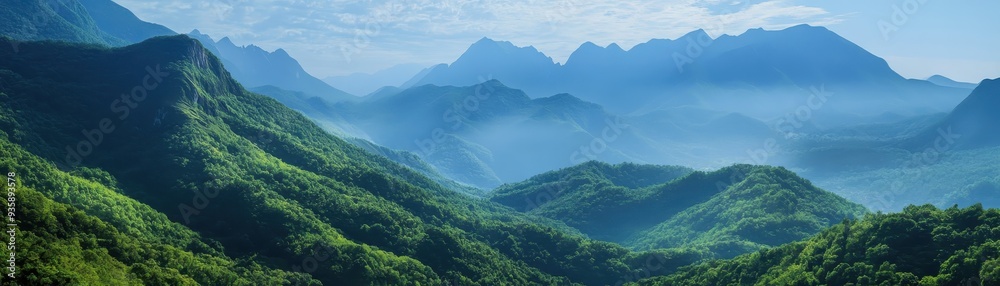 Fototapeta premium Beautiful panoramic view of lush green mountains with a misty sky background, creating a serene and natural landscape scene.