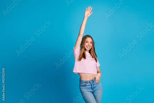 Photo portrait of attractive young woman raise hand dancing dressed stylish striped pink clothes isolated on blue color background