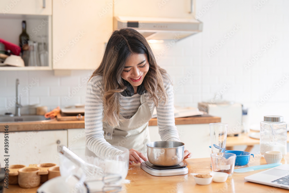 Smiling woman weighing ingredients in a modern kitchen
