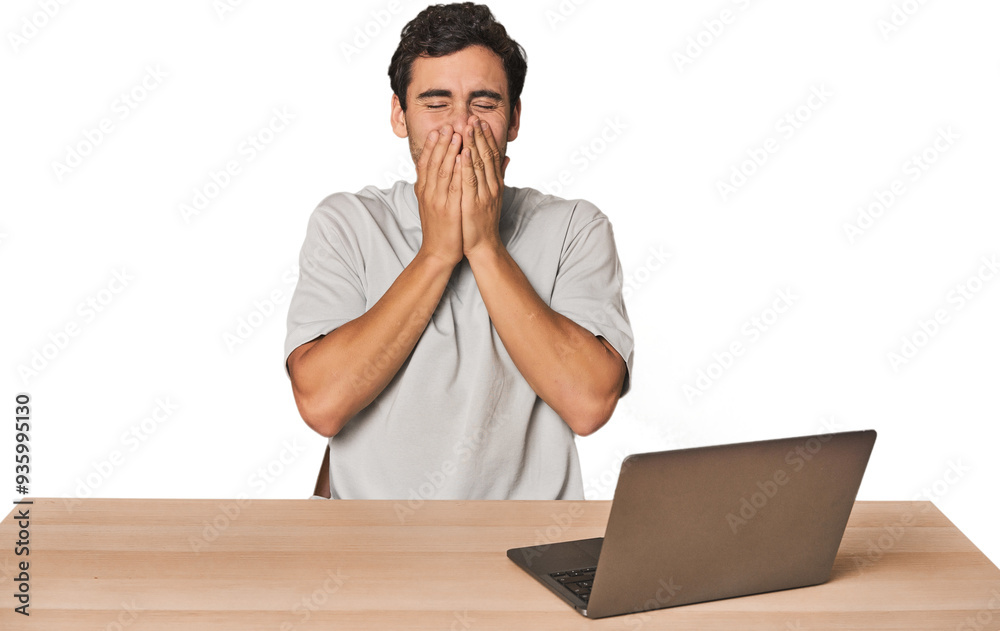 Hispanic young man working on laptop laughing about something, covering mouth with hands. Hispanic young man working on laptop laughing about something, covering mouth with hands.