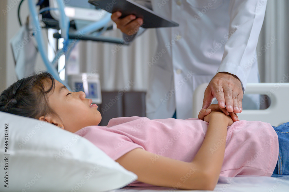 Obraz premium A doctor examines a girl lying on a hospital bed while holding her hand and encouraging her to visit Pediatrics Healthcare. The doctor is performing a health check on the young patient.