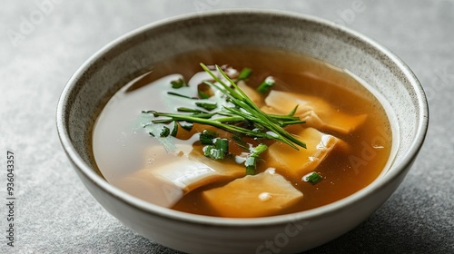 Premium shark fin soup in a deep dish, the clear and rich broth isolated on a smooth grey background.