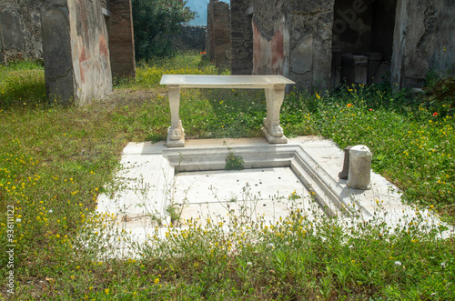 Atrium with Impluvium and marble cartibulum in house in Pompeii in Italy, Europe. Courtyard of house with table and small pool photo