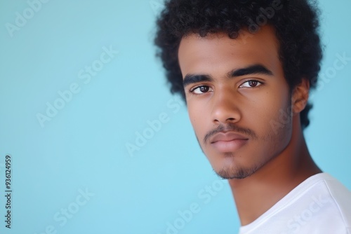 A studio close-up portrait of a young black man wearing a casual t-shirt, with a colourful background.