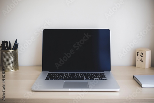 A laptop is open on a desk with a pen and a small wooden box