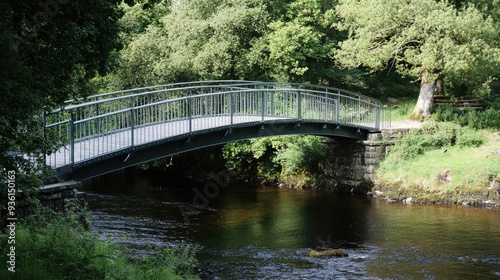 A serene footbridge with a wooden path leading into a lush green park, surrounded by vibrant trees and natural scenery...