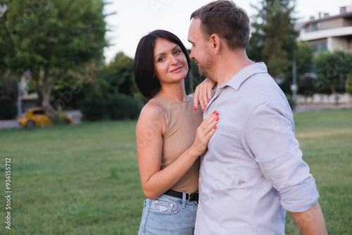 A happy smiling couple walking, hugging and kissing in park on late summer sunset photo