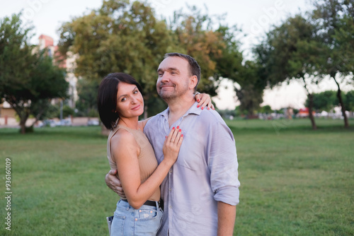 A happy smiling couple walking, hugging and kissing in park on late summer sunset photo