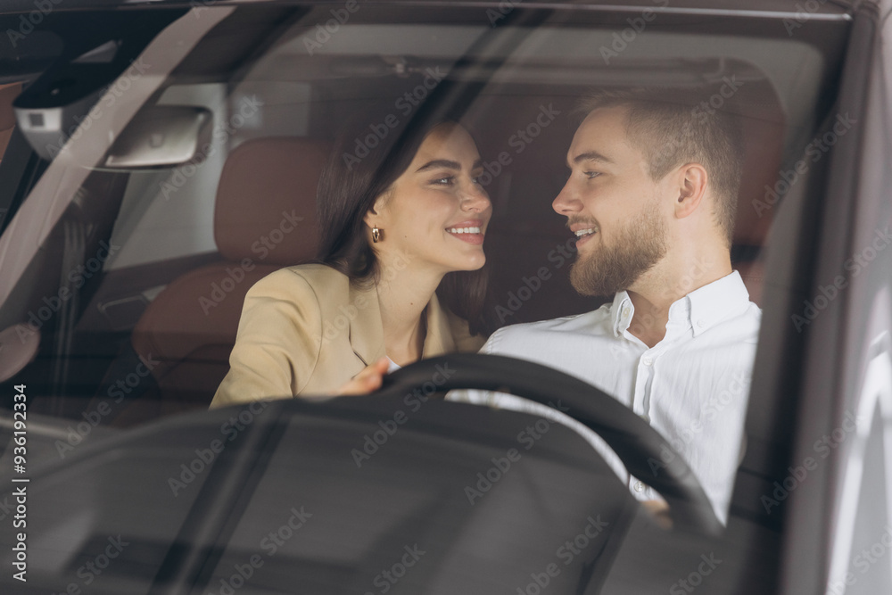 Portrait of smiling beautiful couple sitting in modern luxury car, happy excited young man and woman buying new car in dealership. Portrait of smiling beautiful couple sitting in modern luxury car, happy excited young man and woman buying new car in dealership.