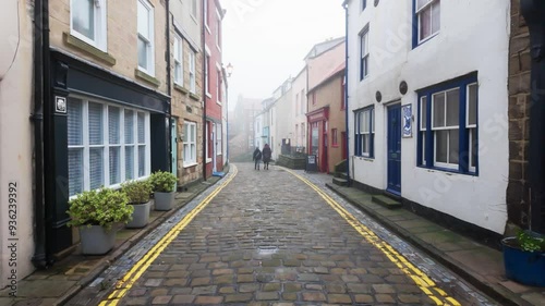 People walking along the quite streets of Staithes a sleepy fishing village on the Yorkshire coast of England. With cobbled streets and old stone built houses. Harbor walls and friendly public houses.