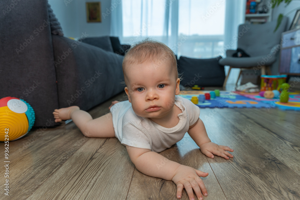 Naklejka premium Pociecha w jasnym pajacyku, przemieszczająca się na czworakach lub próbująca stanąć na drewnianej posadzce. Postać dziecka ukazana jest od pleców, zwrócona w kierunku przedsionka lub wnęki.