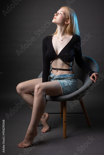 Portrait of a blonde woman with freckles in a sexy top and denim shorts in a studio.