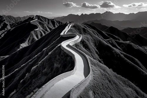 A winding road climbs through a majestic mountain range, creating a dramatic landscape under a cloudy sky. photo