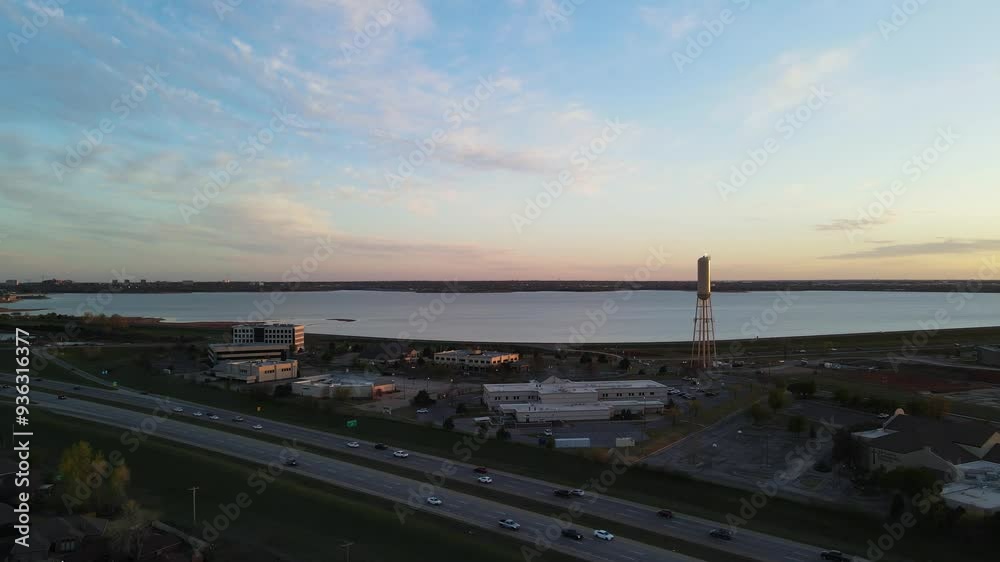 Aerial dolly shot of cars driving across busy freeway in front of industrial city and vast Lake Hefner, Oklahoma City. Aerial dolly shot of cars driving across busy freeway in front of industrial city and vast Lake Hefner, Oklahoma City.