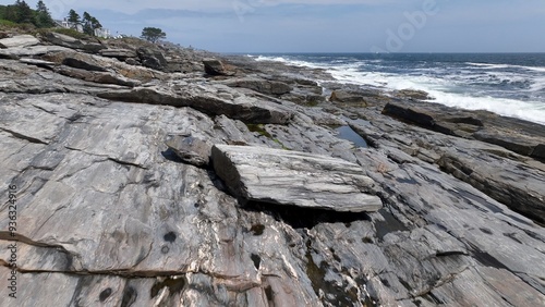 Living beside the Ocean along the rocky coastline in Maine as waves break on beach in summertime
