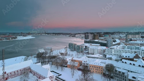 Winter in Scandinavia. Flying over white Aalborg at sunset. Skyline panoramic aerial view of city covered with snow. North Jutland, Denmark