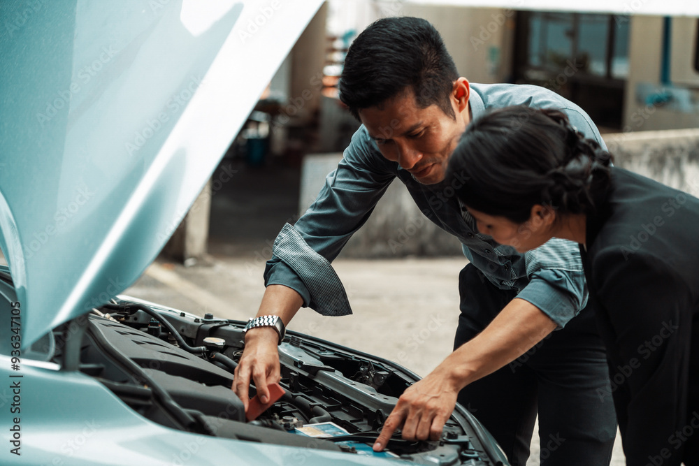 Man help woman fix the car problem. He pop up the car hood to repair the damaged part. uds Man help woman fix the car problem. He pop up the car hood to repair the damaged part. uds