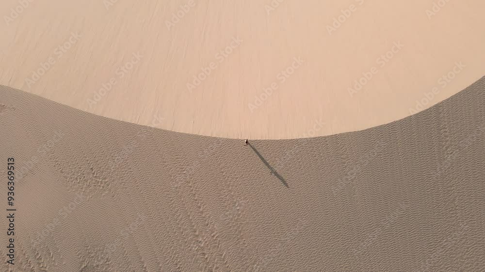 Pessoa andando nas dunas no por do sol com imagem de drone