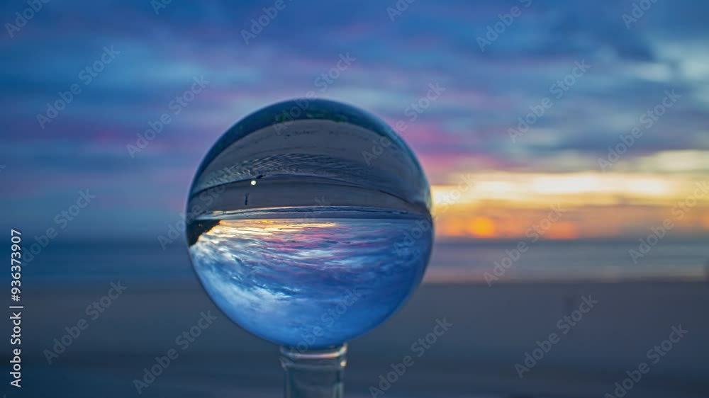 Time lapse A creative capture of a sunset at the beach, viewed through a crystal ball that inverts and magnifies the vibrant colors of the sky and ocean. The blurred background enhances the surreal Time lapse A creative capture of a sunset at the beach, viewed through a crystal ball that inverts and magnifies the vibrant colors of the sky and ocean. The blurred background enhances the surreal