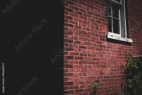 Close up detailed photograph of a vibrant, vintage old red brick building cast with a dark diving shadow. photo