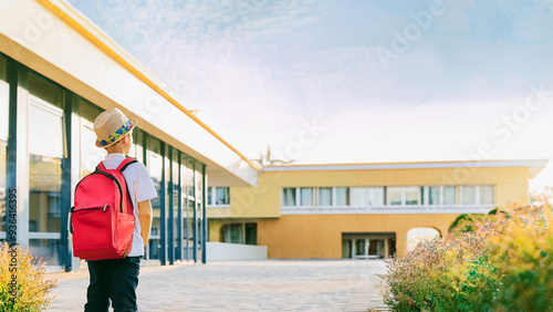 Young boy with backpack and hat walking to school