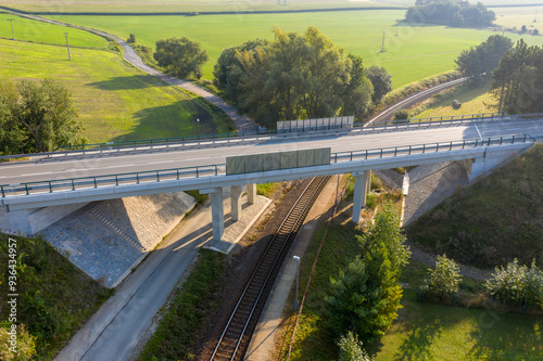 Reinforced Concrete road bridge over railway track during summer. Concrete suspension bridge surrounded by green meadows. 