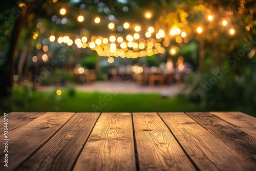 Empty Wood table top with decorative outdoor string lights hanging on tree in the garden at night time
