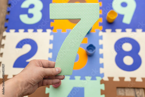 Dłoń osoby trzyma jasnozieloną, piankową cyfrę 