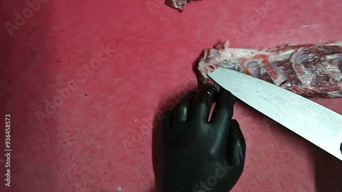 A close-up shot of fresh raw meat being carefully cut on a wooden board. The meat is vibrant and high-quality, with a sharp knife slicing through it, highlighting the precision and skill photo