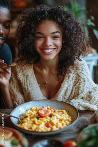 A joyful woman enjoying a delicious pasta dish with a smiling companion at a ...