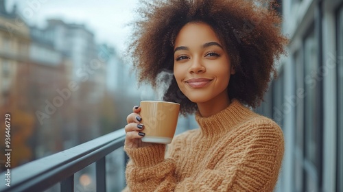 Young woman enjoys coffee on a balcony in a cozy sweater during a chilly morning