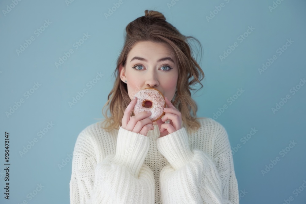 A young woman playfully holds a donut in front of her mouth. She wears a cozy sweater and has wavy hair. This image captures joy and delicious treats. Generative AI A young woman playfully holds a donut in front of her mouth. She wears a cozy sweater and has wavy hair. This image captures joy and delicious treats. Generative AI