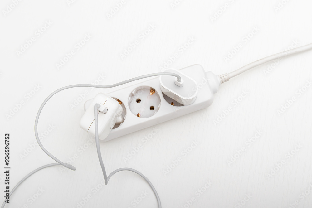 Power strip with many plugs on whitebackground. Overload of the electrical network. A lot of charges wires in the extension cord. Top view Power strip with many plugs on whitebackground. Overload of the electrical network. A lot of charges wires in the extension cord. Top view