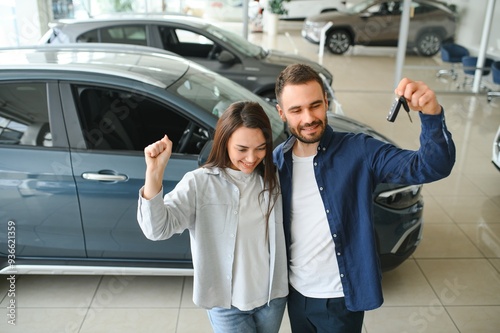 Portrait of a beautiful young couple choosing a new car at a car dealership