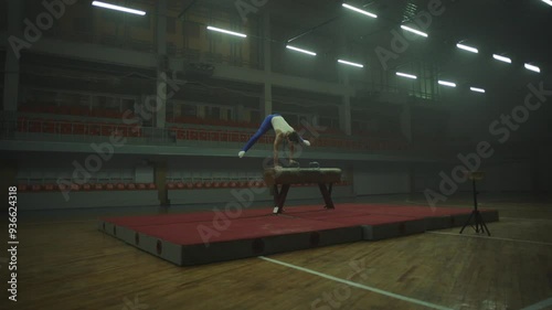 A male gymnast practicing alone at the gym and doing headstand photo