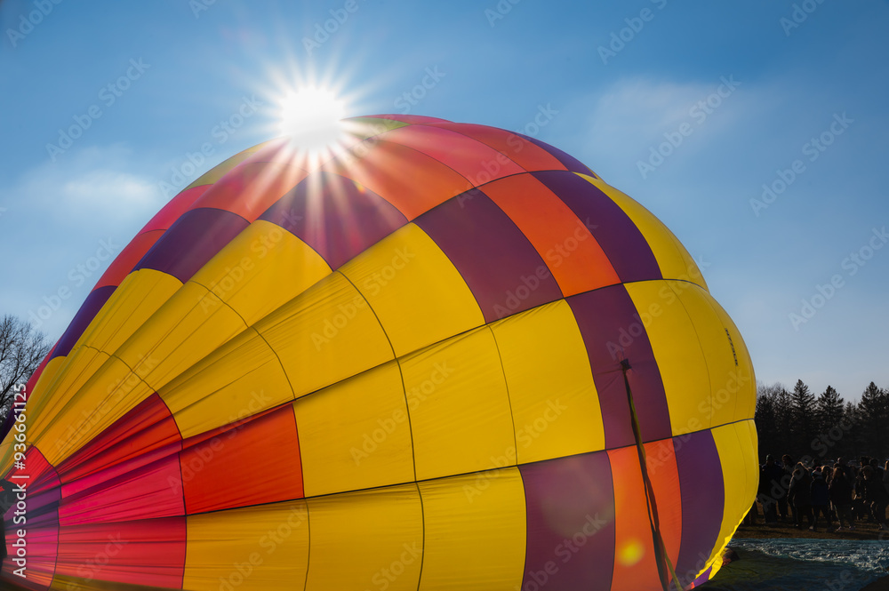 Obraz premium Hot air balloon being inflated with sun flare with blue sky behind