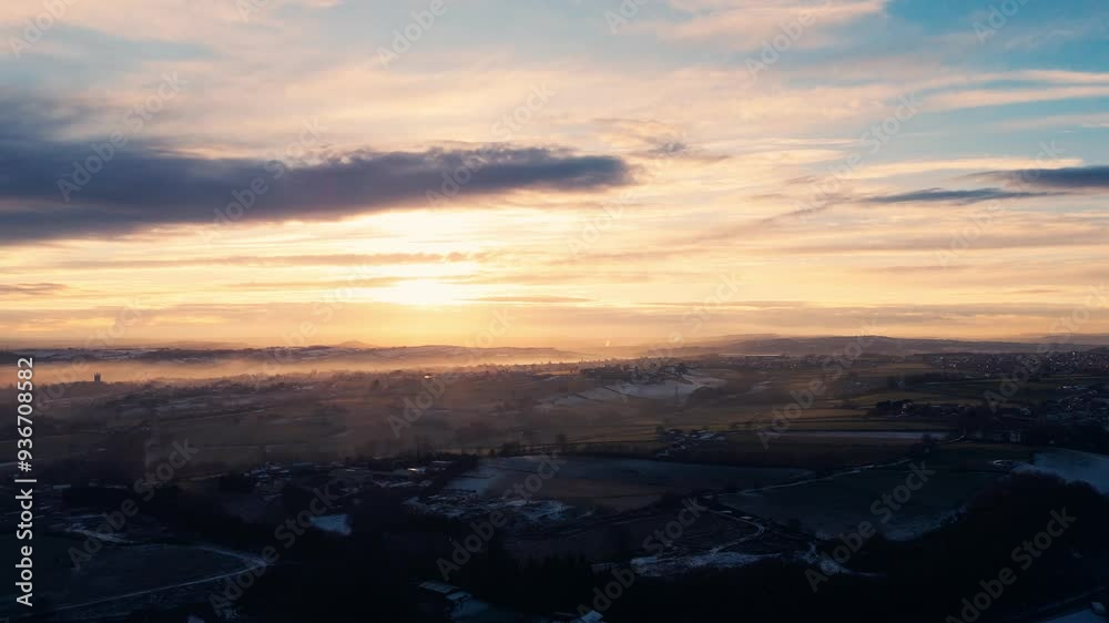 Misty, urban January winters sunset with sun-rays breaking through the mist. Yorkshire aerial scene with red brick houses, industrial buildings, Soft distant mist covering rolling hills and dales. Misty, urban January winters sunset with sun-rays breaking through the mist. Yorkshire aerial scene with red brick houses, industrial buildings, Soft distant mist covering rolling hills and dales.