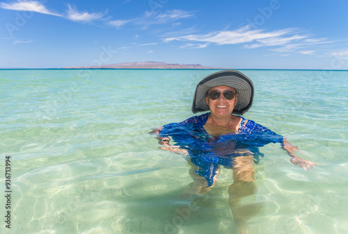 Mature Mexican woman posing happily for her summer vacation portrait in the crystal clear waters of El Tecolote beach in La Paz BCS Mexico photo