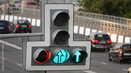 A complex traffic light that regulates car traffic and shows both a green permissive arrow and a red prohibitive signal for cars turning left. Turning left is prohibited according to the traffic light