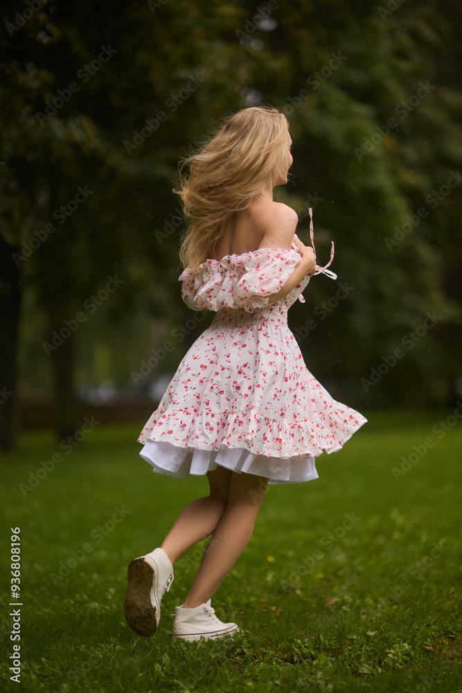 A Beautiful and Elegant Young Woman in a Lovely Summer Dress Posing Gracefully Outdoors A Beautiful and Elegant Young Woman in a Lovely Summer Dress Posing Gracefully Outdoors