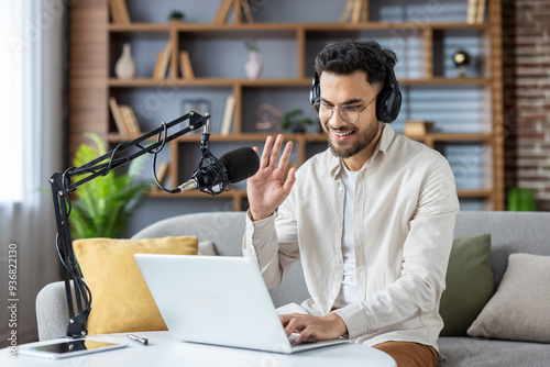 Photography Smiling young man with headphones recording podcast from home office with laptop