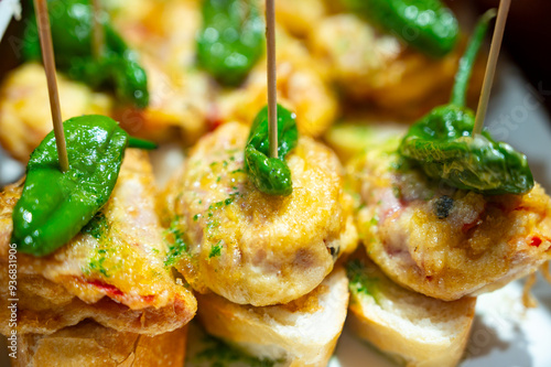 Typical snack of Basque Country, pinchos or pinxtos skewers with small pieces of bread, fish, sea food, sweet green pepper served in bar in San-Sebastian or Bilbao, Spain, close up photo