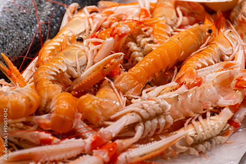 Assortment of fresh daily catch of prawns, seashells, molluscs on ice on fish market in Brittany, France, English translation: differens French names of seafood