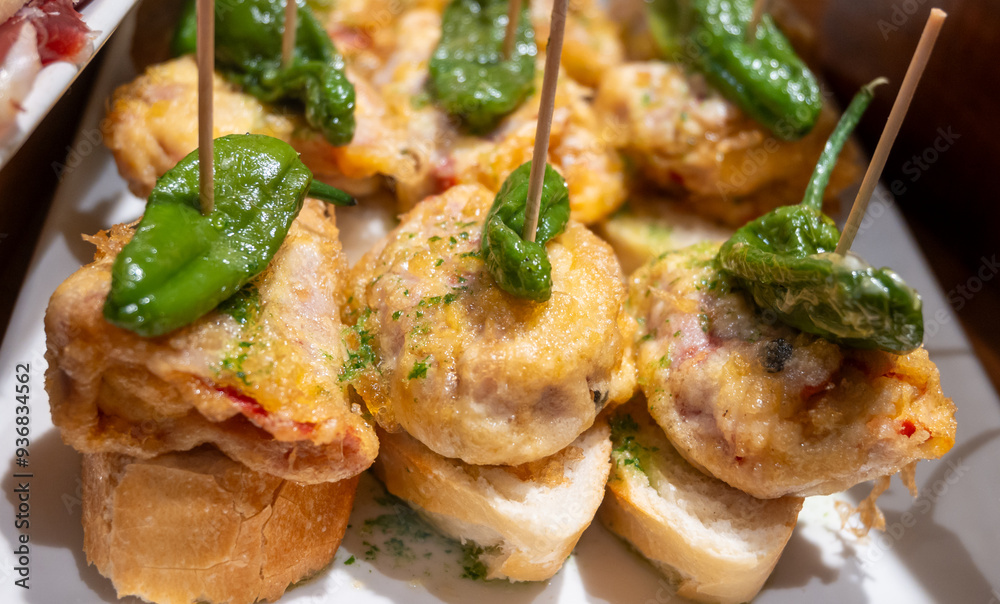 Typical snack of Basque Country, pinchos or pinxtos skewers with small pieces of bread, fish, sea food, sweet green pepper served in bar in San-Sebastian or Bilbao, Spain, close up Typical snack of Basque Country, pinchos or pinxtos skewers with small pieces of bread, fish, sea food, sweet green pepper served in bar in San-Sebastian or Bilbao, Spain, close up