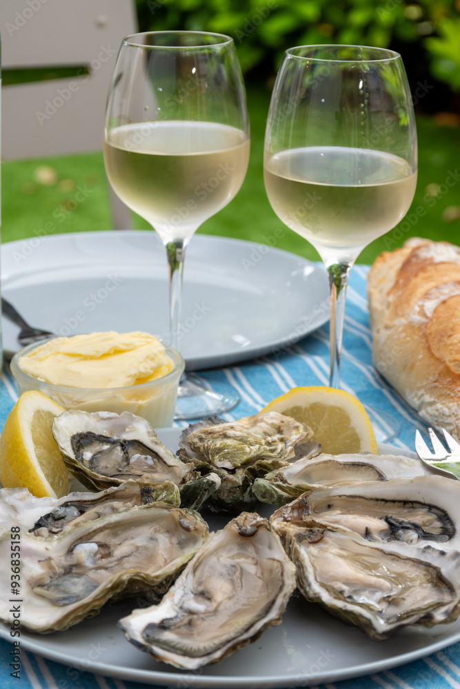 Plate with fresh live oysters with citron, bread, butter and white wine served at restaurant in oyster-farming village, Arcachon bay, Gujan-Mestras port, France