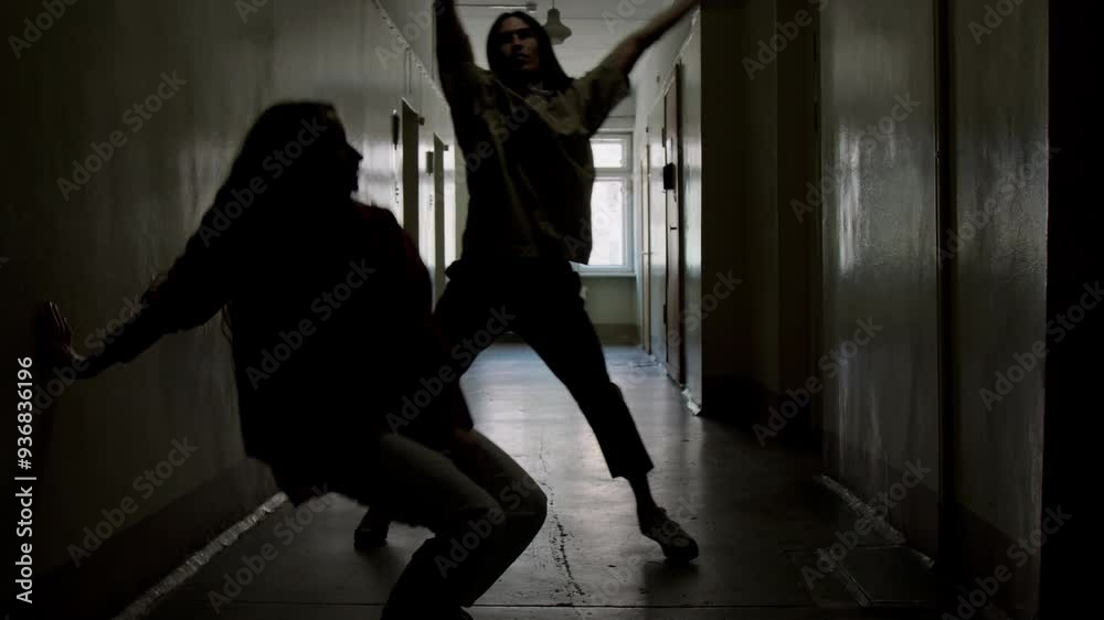 Full shot of backlit silhouettes expressive couple performing contemporary dance in dark hallway Full shot of backlit silhouettes expressive couple performing contemporary dance in dark hallway